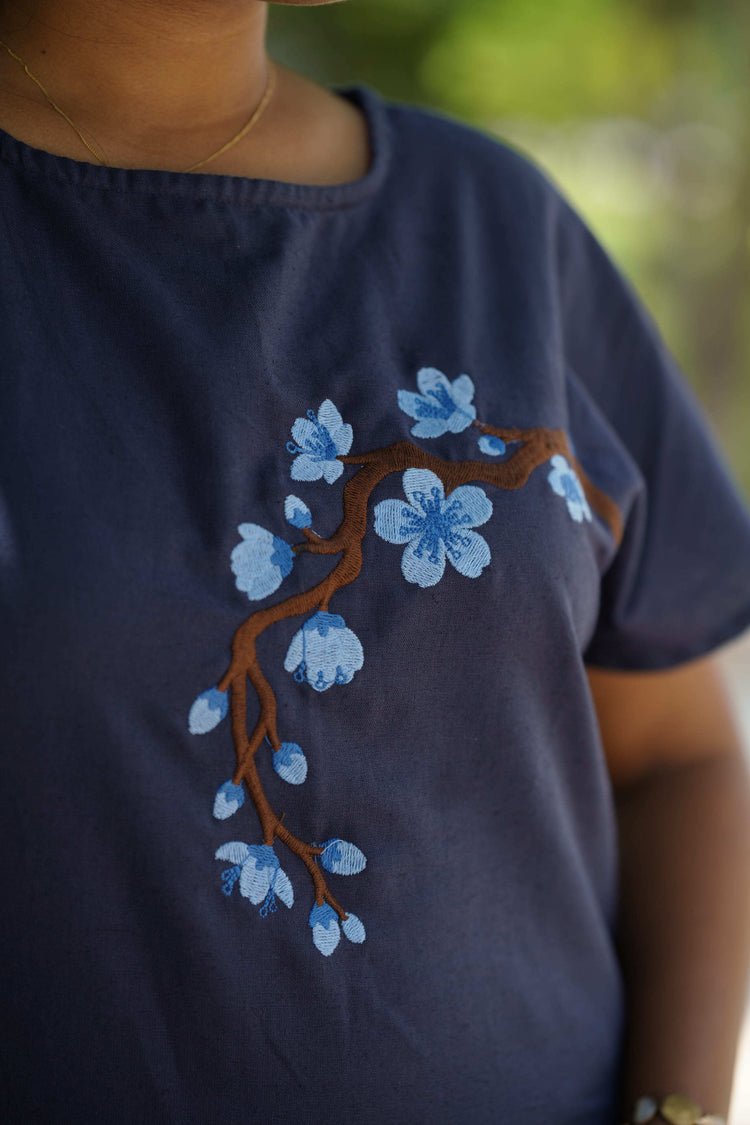 Close-up of hand-finished floral embroidery on a navy co-ord