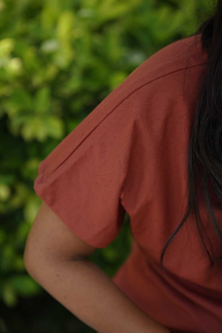 Close-up of brick red cotton-flax fabric texture on the shoulder and sleeve